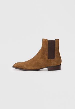 Brown suede ankle boot with a sleek design, elastic side panels, a rounded toe, and a low stacked heel.