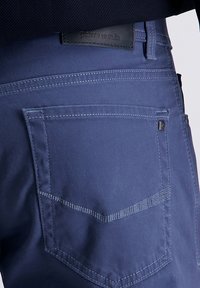 Dunkelblaue Denim-Jeans mit einer aufgesetzten Tasche und markanten Nähten auf der Rückseite. Verfügt über ein schwarzes Leder-Logolabel am Bund.
