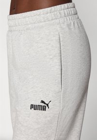 Light grey sweatpants made of a soft, textured material; features an elastic waistband and a black embroidered Puma logo near the pocket.