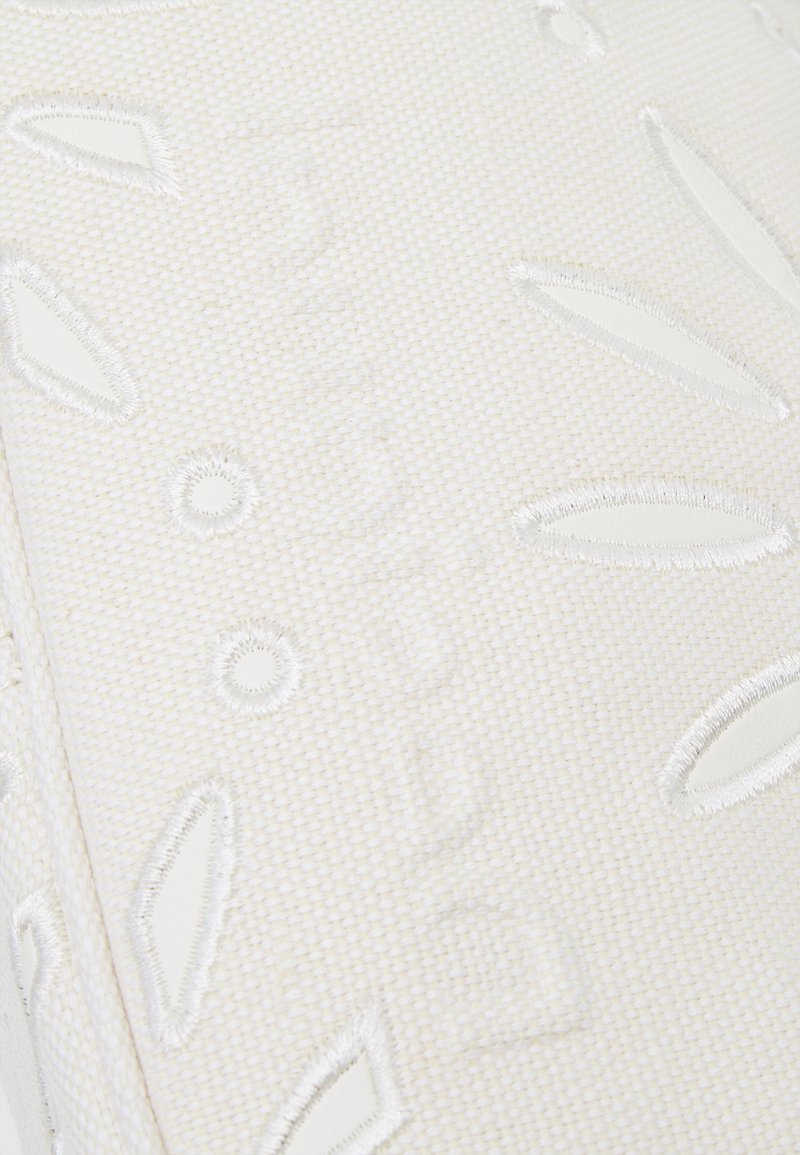 Producto textil blanco con patrones de hojas elevados y círculos; textura suave con detalles en relieve. Diseño limpio y minimalista.