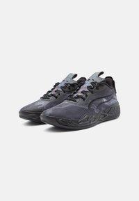 Baskets de sport noires avec une tige texturée, des motifs en vagues, un bout arrondi et une semelle épaisse avec un motif. Elles présentent des lacets noirs et des accents réfléchissants.