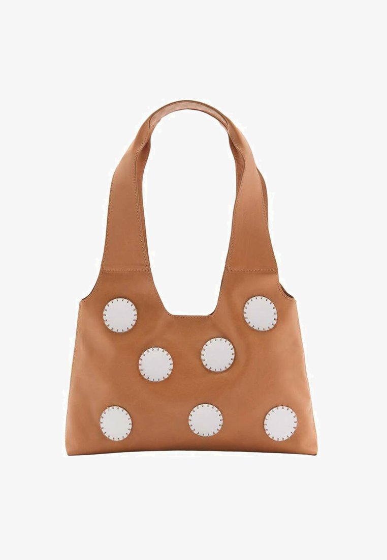 Sac à main en cuir tan avec une large bandoulière, comportant huit accents circulaires blancs et des détails cousus. Design épuré avec une découpe centrale.