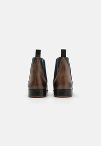 Botine Chelsea din piele maro, cu părți elastice navy și accente texturate, având o finisare netedă și tab-uri pentru un acces ușor.