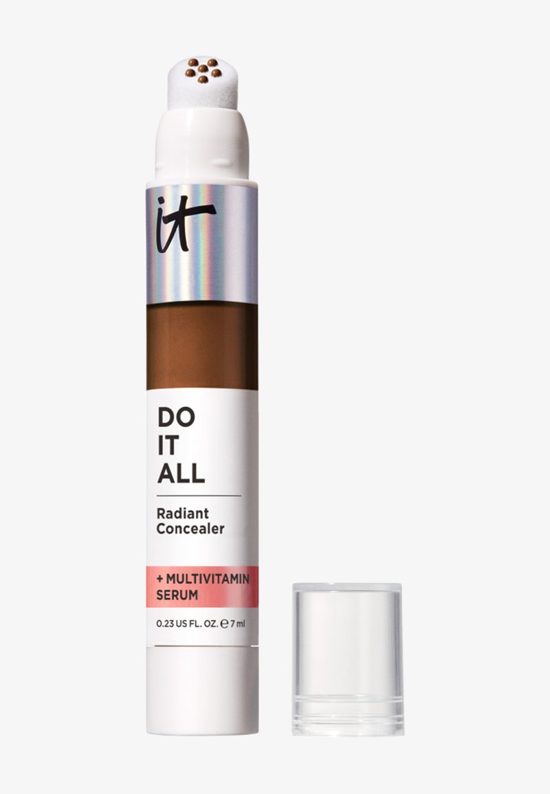 Bâton correcteur avec embout en éponge arrondi et six petits points de maquillage, étiqueté "Correcteur Rayonnant Tout-en-un + Sérum Multivitaminé".