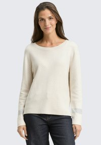 Maglione lungo a maniche con tessuto beige chiaro, caratterizzato da un motivo testurizzato e strisce grigie sui polsini. Realizzato in tessuto morbido, presenta un collo ampio.