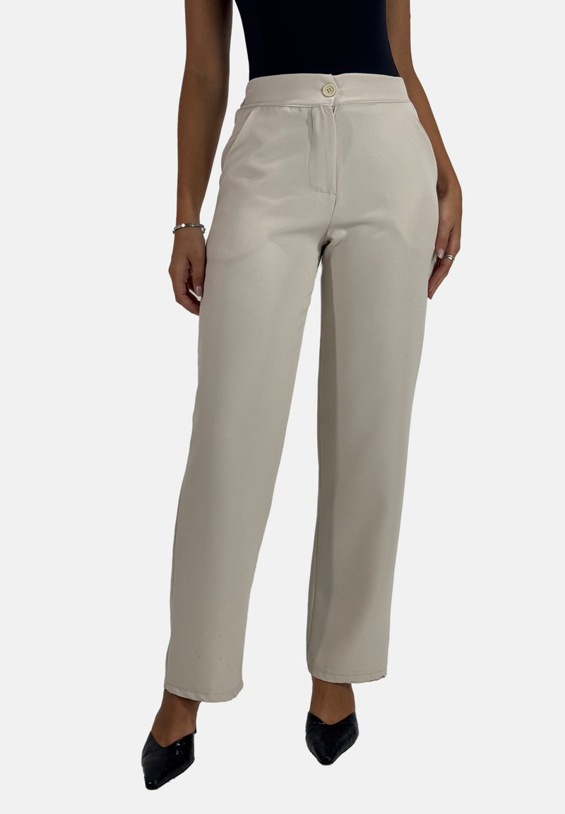 Beige wijde pantalon met een gladde textuur, sluiting met een knoop aan de voorkant en zijzakken. Gepaard met zwarte puntige schoenen.