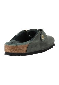 Grüner Wildleder Slipper mit Korksohle, flauschigem Innenfutter und einem einzelnen Riemen mit einem runden Metallknopf-Detail.