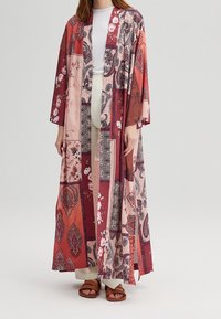 Kimono-style robe with a patchwork design featuring red, pink, and floral patterns. Made of lightweight fabric with wide sleeves.
