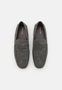 Grijze suède loafers met een platte zool, gestikte details en een decoratieve leren band over de wreef. Soepele textuur, minimaal design.