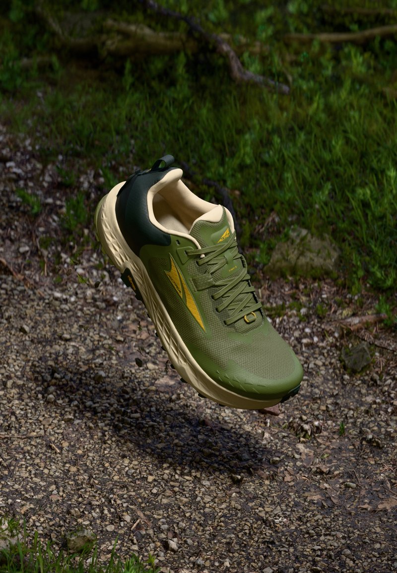 Green and beige running shoe with mesh upper, textured patterns, padded collar, and a rubber outsole, featuring a yellow logo accent.