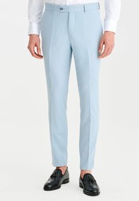 Jasnoniebieskie dopasowane spodnie o gładkiej fakturze, z prostym przodem i dwiema bocznymi kieszeniami, w połączeniu z czarnymi loafersami.