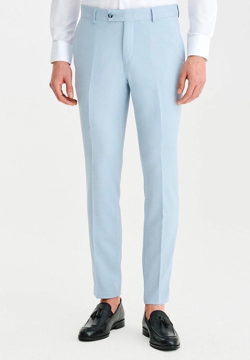 Jasnoniebieskie dopasowane spodnie o gładkiej fakturze, z prostym przodem i dwiema bocznymi kieszeniami, w połączeniu z czarnymi loafersami.