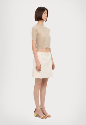 Beige, kortstrikket topp med korte ermer, kombinert med en hvit A-linje skjørt og gule høyhelete sandaler. Glatt tekstur, minimalistisk design.
