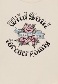 Tissu beige clair avec un design graphique comprenant des roses roses, une bannière bleue avec "VRAI AMOUR" et un texte gothique lisant "Âme sauvage" et "éternellement jeune".