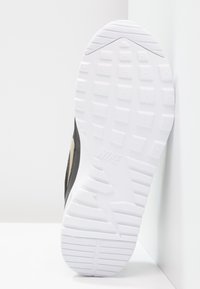 Black athletic shoe sole with textured white rubber, featuring hexagonal patterns and a logo. Side accents in a light color.