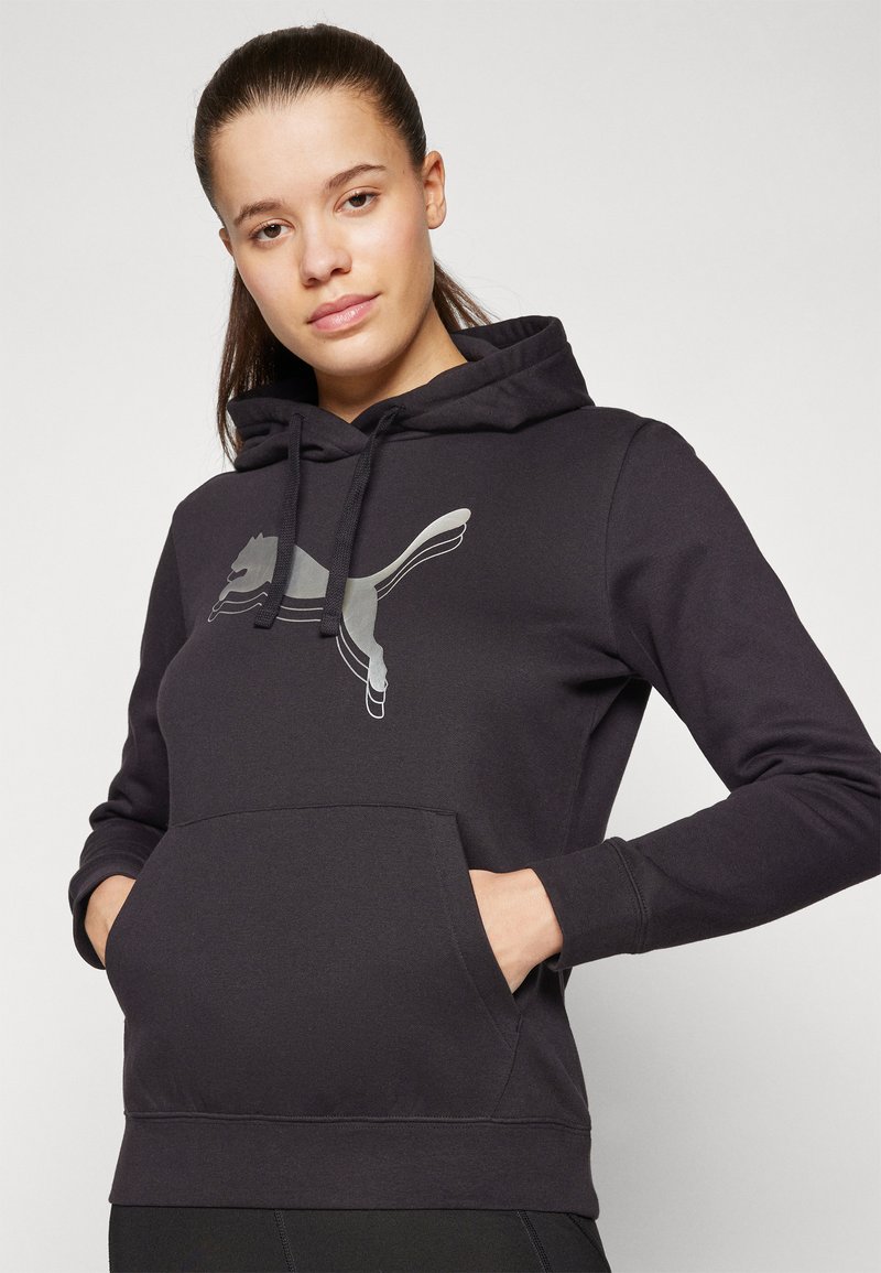 Schwarzer Kapuzenpullover mit großem reflektierendem grauem Puma-Logo auf der Vorderseite und einer Kängurutasche auf Höhe der Taille.