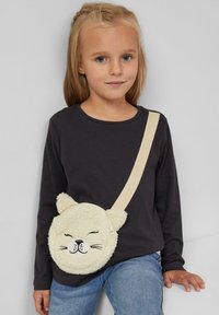 Kremowa, okrągła torebka na ramię z designem twarzy kota, puszystą teksturą i akcentami uszu. Posiada regulowany pasek i zamek błyskawiczny.