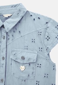 Light blue shirt with floral embroidery, short sleeves, collar, and a chest pocket featuring a heart-shaped metal logo.