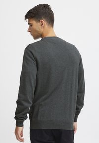 Suéter de punto gris oscuro con mangas largas y cuello redondo. Presenta un dobladillo y puños acanalados, y una textura suave. Sin patrones ni adornos visibles.
