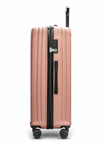 Maleta rígida en rosa suave con acabado texturizado, cremallera y asa negra, asa retráctil y cuatro ruedas giratorias para facilitar la movilidad.