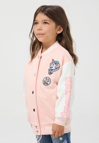 Giacca varsity rosa con maniche bianche, decorata con toppe di unicorno e stelle, bottoni a scatto e polsini a righe. Texture del tessuto morbida.