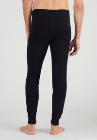 Leggings de algodón negro con un diseño ajustado, que presentan una textura suave y tobillos con puños. La cinturilla es elástica y sin costuras.