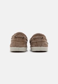 Barna vászon slip-on cipők texturált felülettel, finom varrással és fehér gumitalppal. Két díszítő fűzőlyuk minden oldalán.