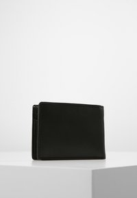 Portafoglio in pelle nera con una superficie liscia, forma rettangolare e dettagli di cucitura visibili. Presenta un profilo sottile e un design compatto.
