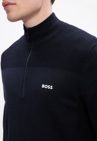 Jūras spēku puszipa džemperis ar ribotu tekstūru, kas piedāvā kontrastējošu gludu paneli un izcelta 'BOSS' logo uz krūtīm.