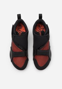 Mustat ja punaiset urheilukengät, joissa on teksturoitu päällinen, hihnakiinnitys ja erottuva kuvioitu sisäpohja. Kevyet ja joustavat pohjat.