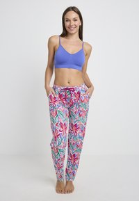 Blauwe bralette en broek met een bloemenpatroon in roze, rood en groene tinten. De broek heeft zakken en een elastische tailleband met koord.