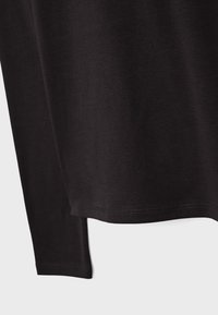 Črna majica z dolgimi rokavi z gladko, bombažno teksturo. Ima okroglo izrez in rahlo ukrivljen spodnji rob.