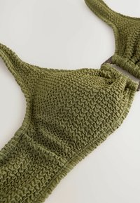 Olivgrüner, strukturierter Bikinioberteil mit gerafftem Design, verstellbaren Trägern und einem subtilen Glanz, hergestellt aus einem dehnbaren Stoff.