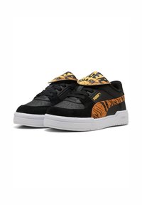 Baskets Puma noires et orange avec des semelles blanches, détails en rayures de tigre sur les côtés, et un rabat orange avec du texte noir sur le dessus.