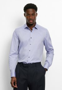 Light purple button-up shirt with long sleeves, featuring a structured collar and subtle texture, paired with dark, pleated trousers.
