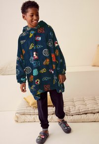 Hættebadekåbe i mørkeblå frotté med farverige sports-inspirerede mærker. Sæt sammen med sorte joggers og grå slip-on sko.