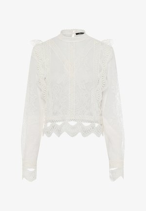 White lace blouse featuring a high neck, long sleeves, ruffled accents, and scalloped hem. Intricate floral patterns enhance the design.