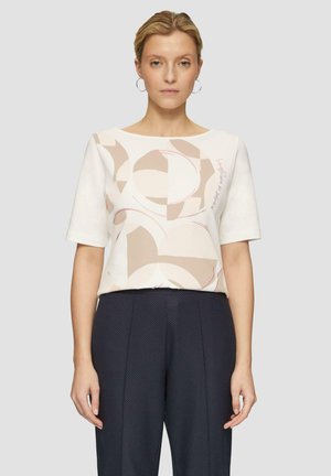 Korte mouwen, losse fitting top in crème, met abstracte vormen in beige en zachtroze. De stof heeft een gladde textuur en een ronde halslijn.