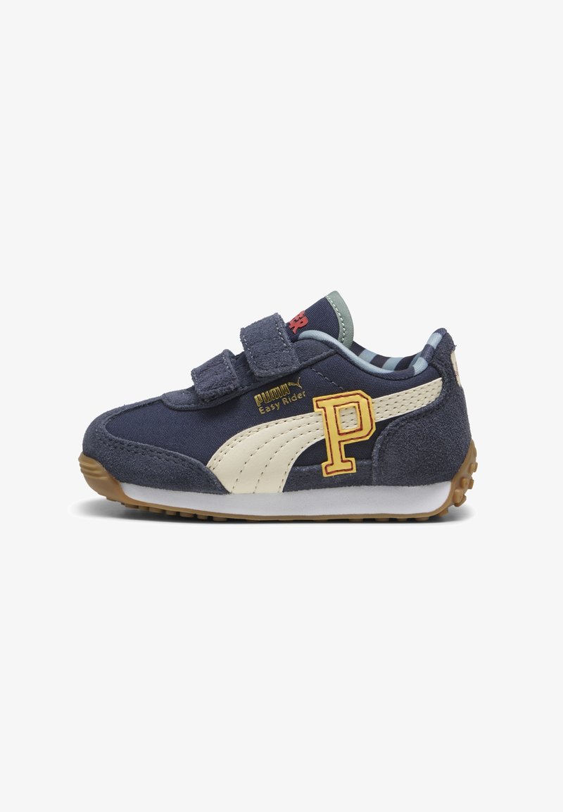 Baskets pour enfant bleu marine avec logo Puma beige, patch "P" jaune, deux sangles velcro et semelle en gomme sur fond blanc.