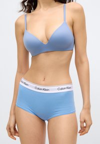 Ανοιχτό μπλε σουτιέν με ομαλή υφή και ρυθμιζόμενους ιμάντες, σετ με αντίστοιχα ανοιχτό μπλε σορτς με λευκή ζώνη μέσης Calvin Klein.