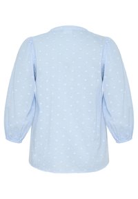 Blouse bleu clair avec des manches ballon, encolure ronde et motif texturé en forme de cœur sur tout le tissu. Matière en coton douce.