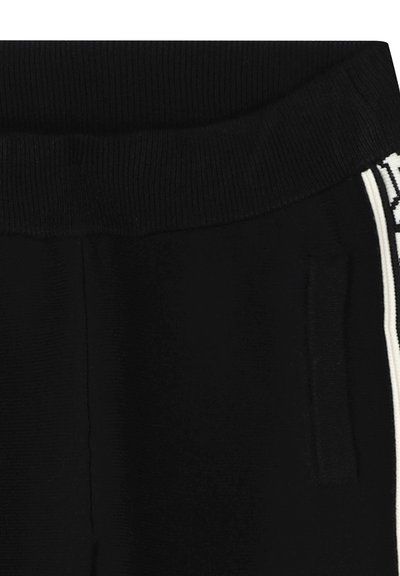 Zwarte joggers met een ribbelachtige elastische tailleband, zijzakken en witte strepen langs de naden. Gladde stoftextuur.