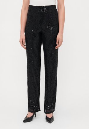 Pantalons noirs en sequins avec une coupe droite, dotés d'une taille lisse et d'une surface brillante. Associés à des talons aiguilles noirs.