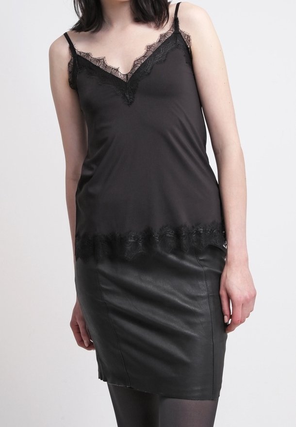 Svart satin camisole med spetsdetaljer vid halsringning och nederkant, tillsammans med en åtsittande svart läderkort klänning. Slät textur genom hela.