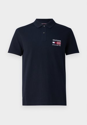 Marineblaues Poloshirt aus Baumwolle mit klassischem Kragen, versehen mit einer Stickerei auf der Vorderseite mit "HILFIGER" und "ESTABLISHED 1985" in Weiß und Rot.