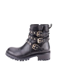 Botín de cuero negro hasta el tobillo con múltiples hebillas en tono dorado y acentos de tachuelas. Presenta una suela robusta tipo lug y un tacón ligeramente elevado.