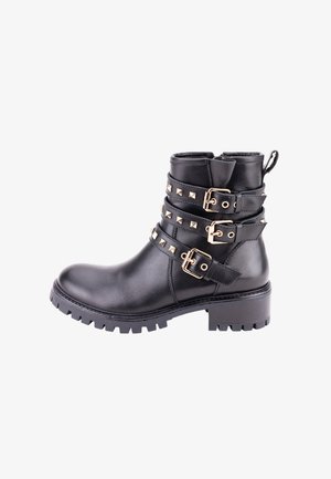 Botte de cheville en cuir noir avec plusieurs boucles en ton doré et des accents cloutés. Présente une semelle à crampons robuste et un léger talon rehaussé.