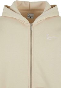 Felpa beige con zip realizzata in tessuto morbido, dotata di cappuccio con coulisse, logo ricamato sul petto e dettagli in zip argentata.