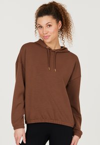 Haut à capuche marron avec un cordon de serrage, des poignets côtelés et un ourlet élastique. Fabriqué en tissu doux avec une coupe décontractée et une texture légère.