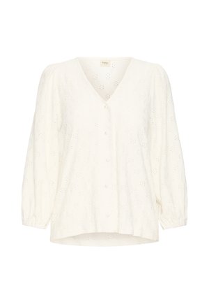 Blouse blanche avec un col en V, manches ballon et fermeture à boutons. Présente des motifs floraux découpés et une finition de tissu texturée.